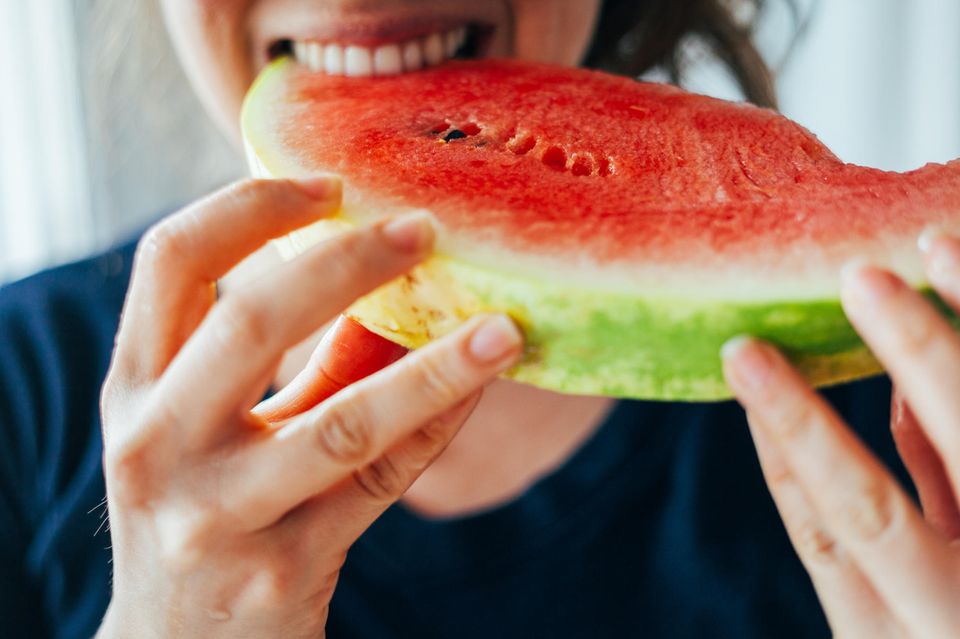 Junge Frau beißt in ein Stück Wassermelone