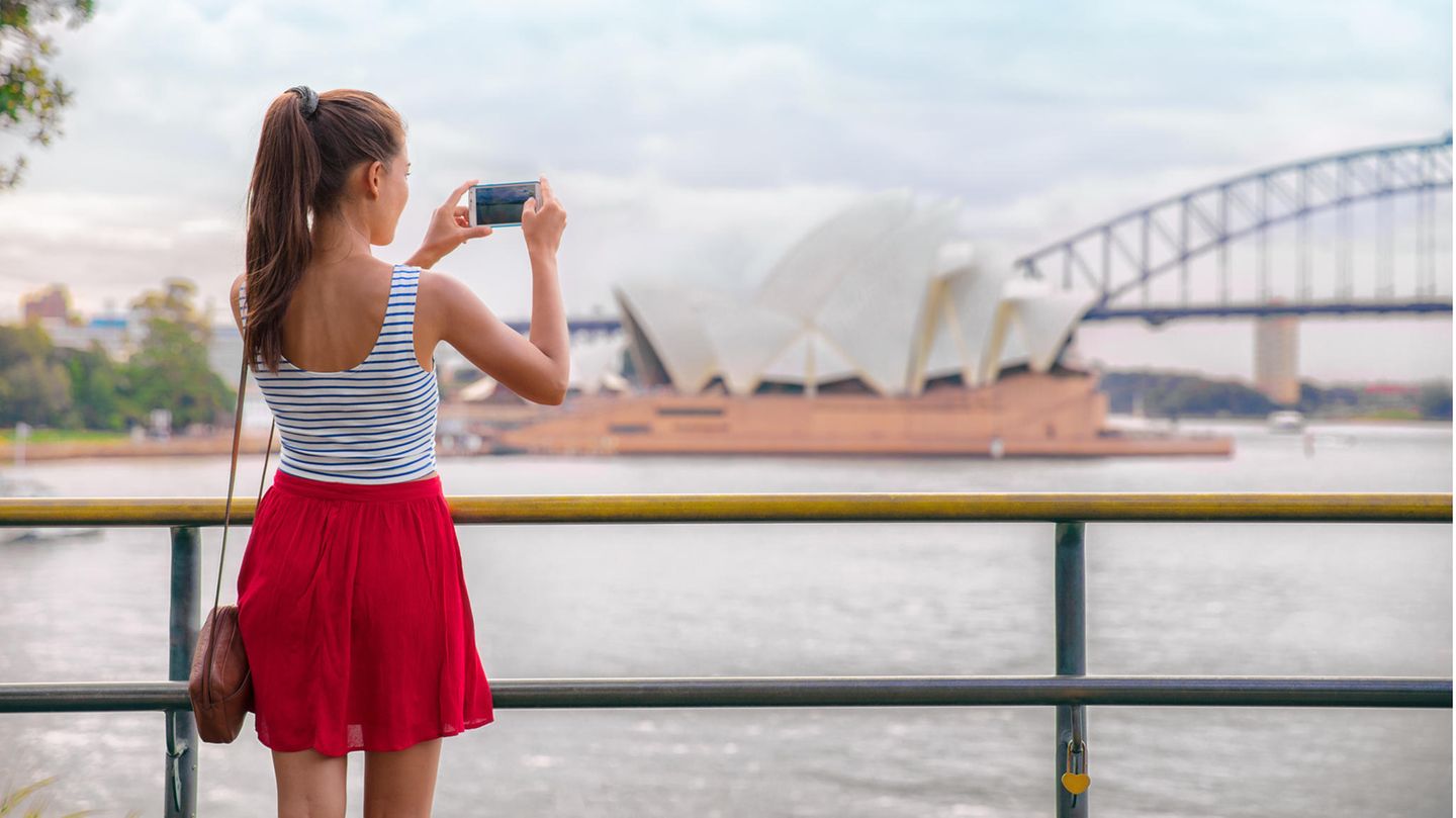 Junge Frau fotografiert die Oper von Sydney mit dem Handy