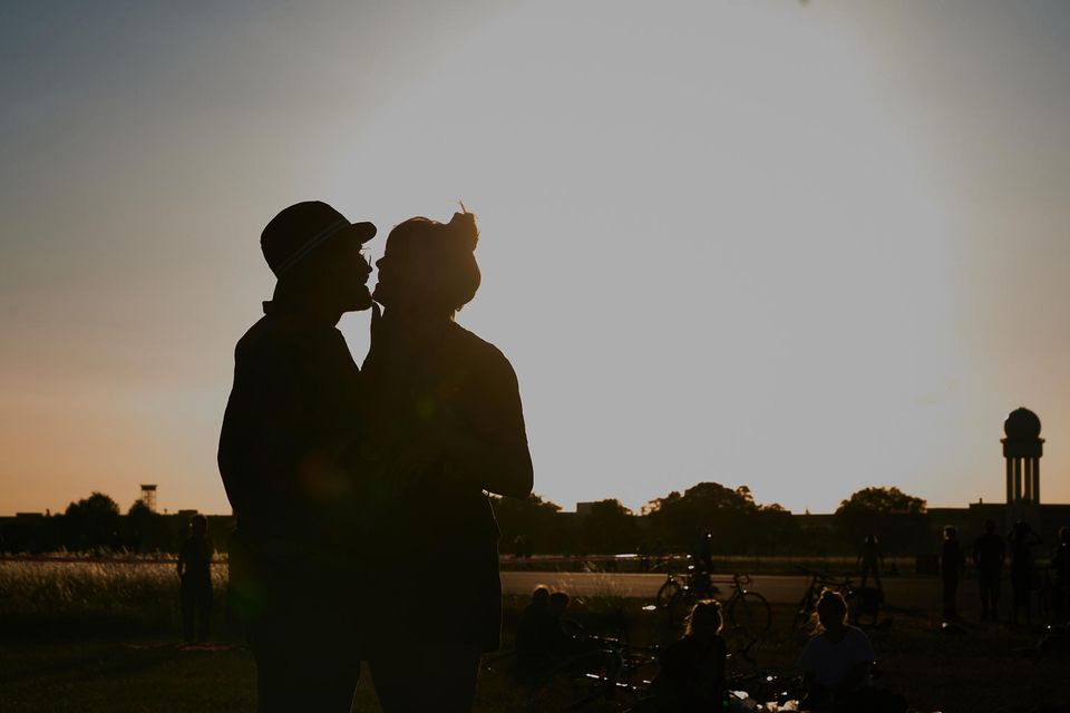 Paar steht auf dem Tempelhofer Feld in Berlin und küsst sich bei Dämmerung
