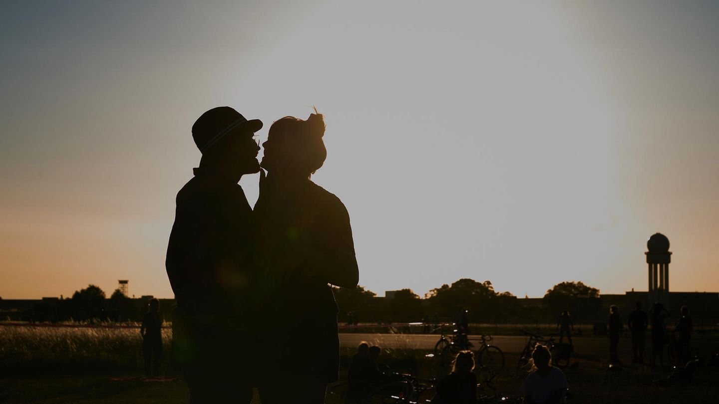 Paar steht auf dem Tempelhofer Feld in Berlin und küsst sich bei Dämmerung