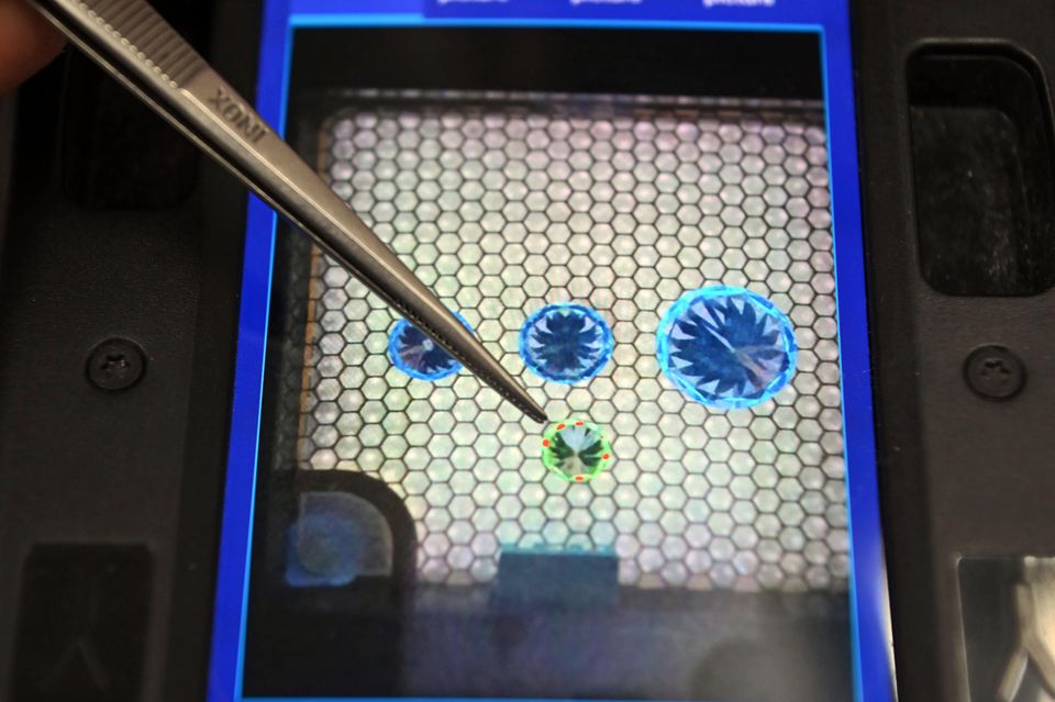 Drei natürliche und ein synthetischer Diamant auf dem Monitor eines Diamantprüfgeräts