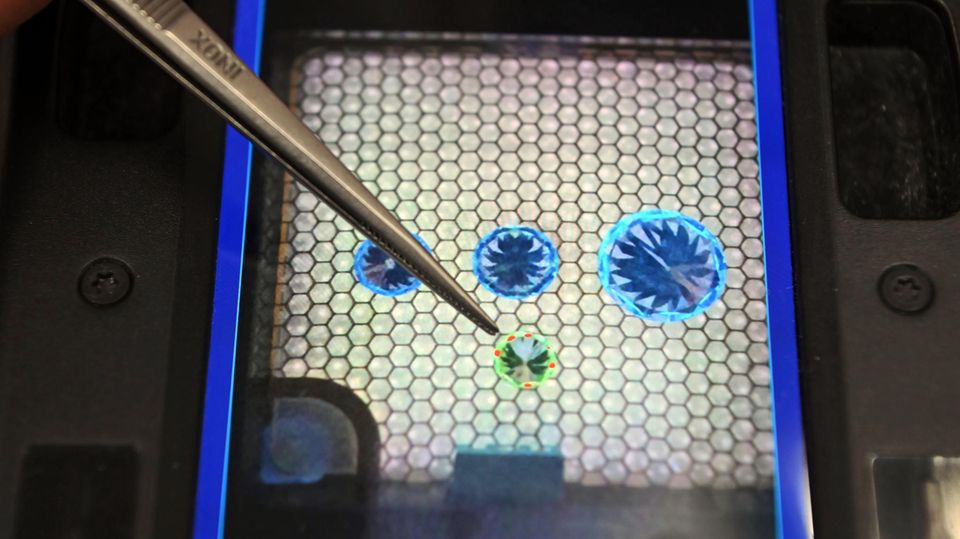 Drei natürliche und ein synthetischer Diamant auf dem Monitor eines Diamantprüfgeräts Drei natürliche und ein synthetischer Diamant auf dem Monitor eines Diamantprüfgeräts