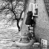 Menschen flüchten über Leitern aus einem gefluteten Haus