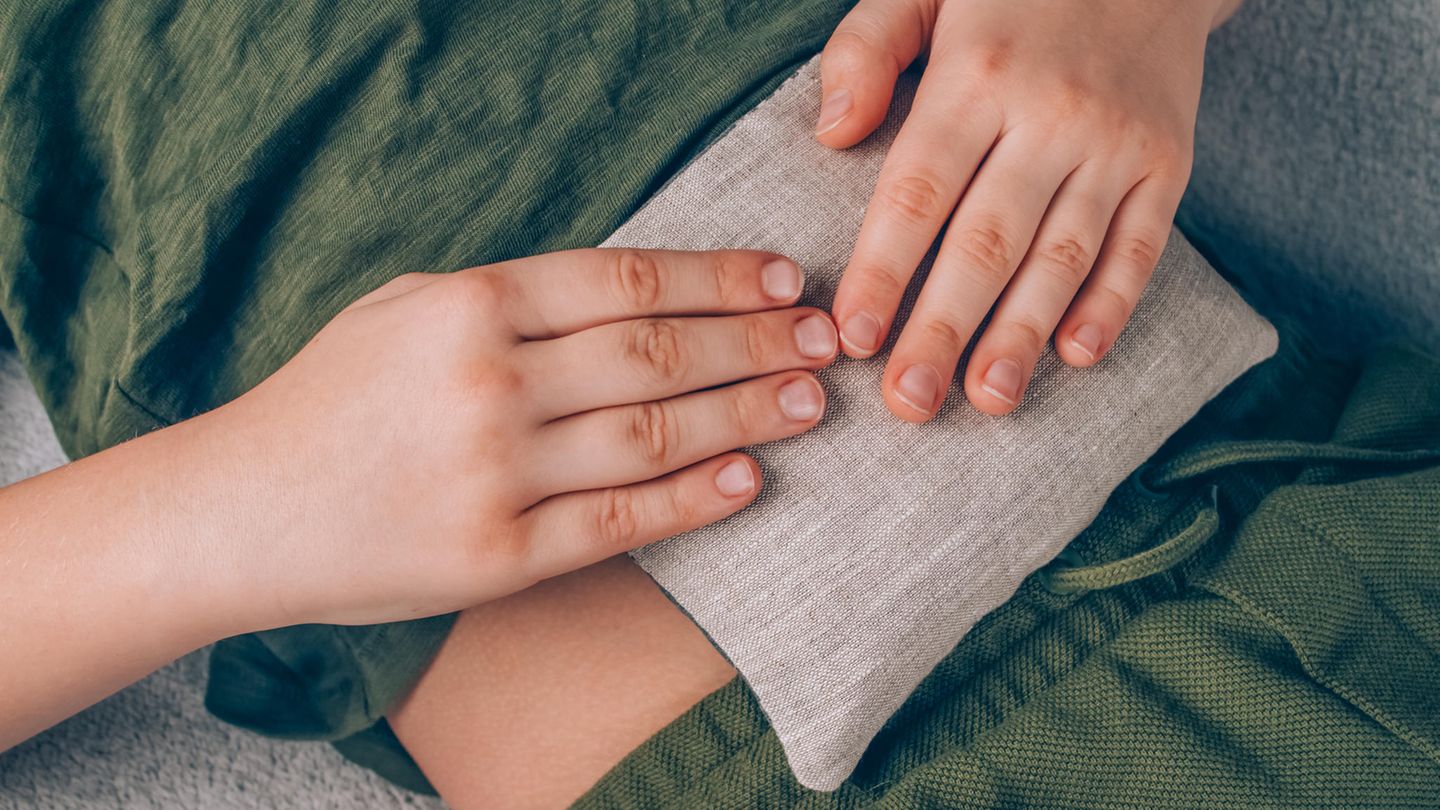 Ein Junge hält ein Körnerkissen auf seinem Bauch fest