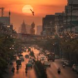 Image Name: Big Statue in the Middle of the City  Photographer Name: Kunuch Chutmongkolporn  Year: 2022  Image Description: <p>This photo was taken in Bangkok, Thailand, on 27 October, 2021. The Big Buddha statue is from Wat Paknam Bhasicharoen. Around the fourth week of October, the sun sets behind the statue. To get a high-impact shot, I used a super-telephoto zoom lens to compress the sun with a bird, the statue, and the city in the foreground.</p>  Copyright: © Kunuch Chutmongkolporn, Thailand, Winner, National Awards, Travel, 2022 Sony World Photography Awards