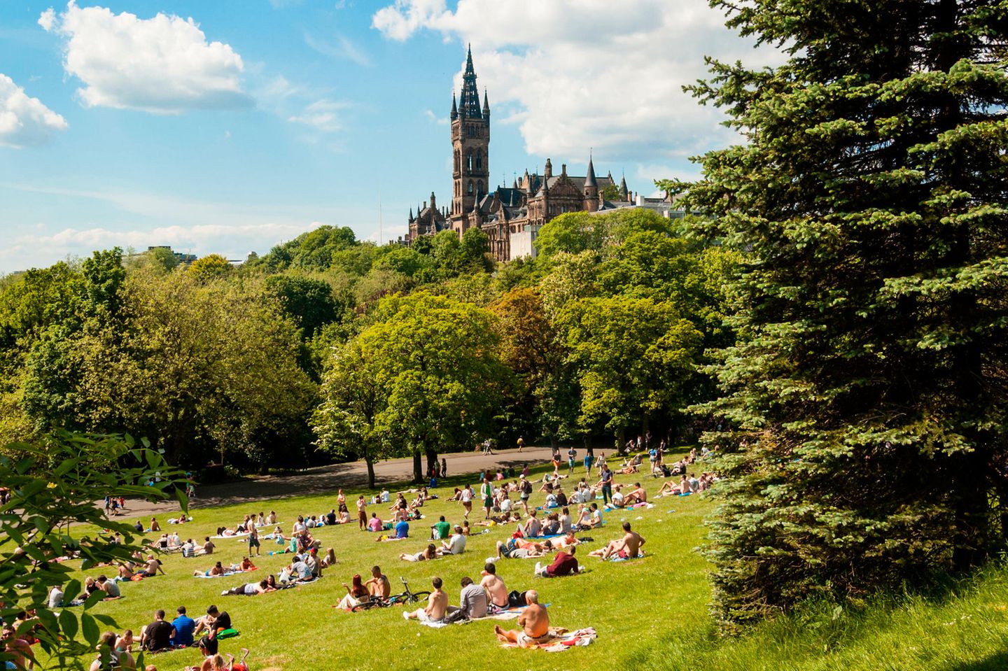 Kelvingrove Park View of Kelvingrove Park full of people enjoying the Scottish summer with main building of Glasgow University on the top of hill