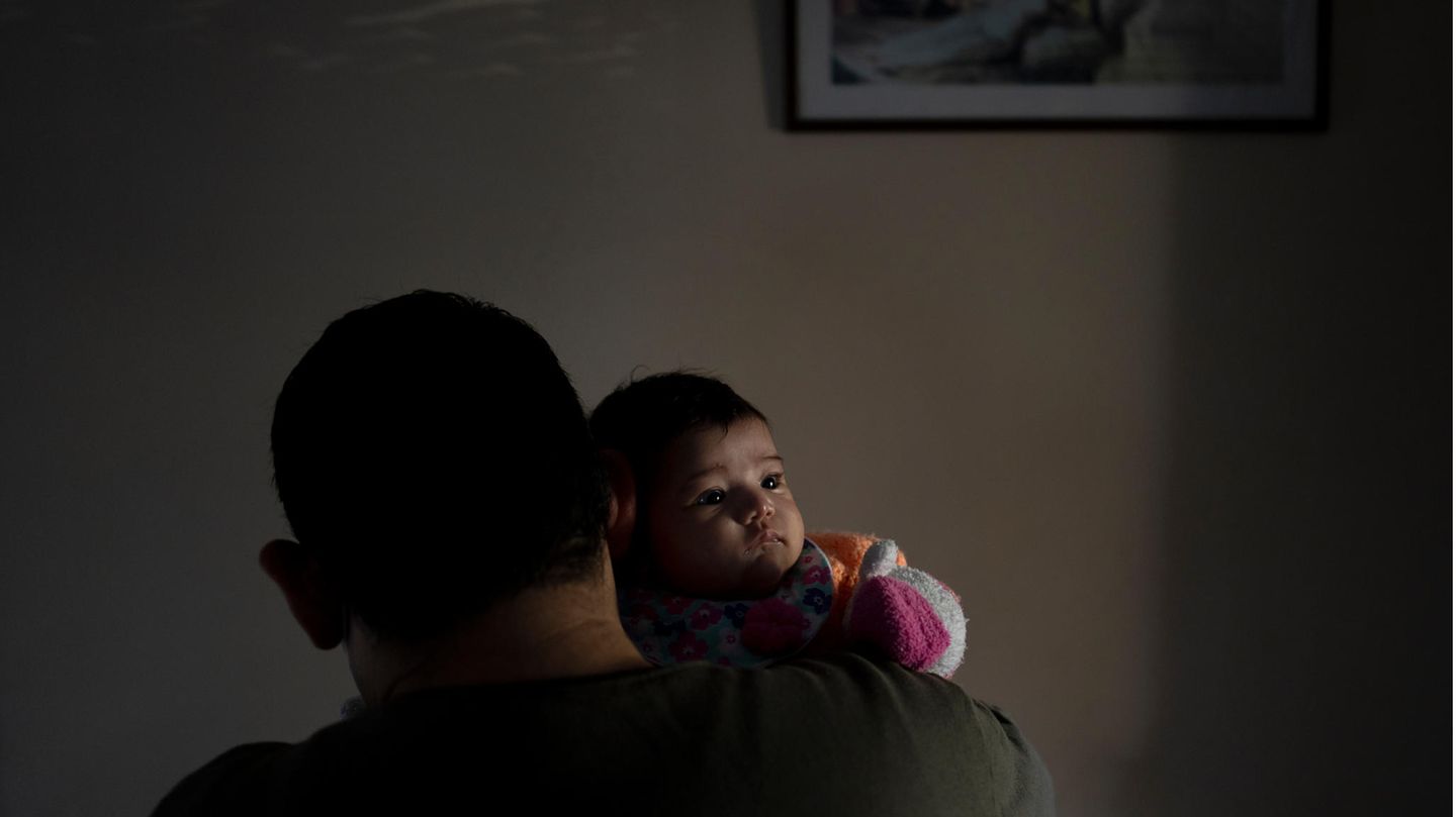 Baby ist auf dem Arm eines Mannes und schaut über dessen Schulter