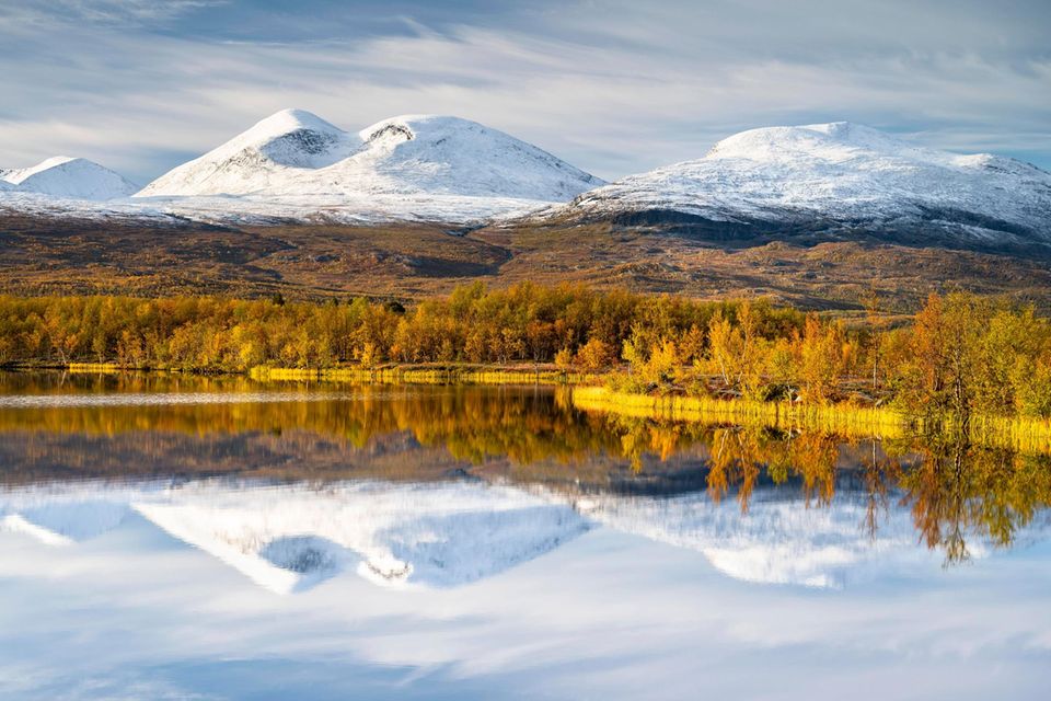 Verschneite Berge im Abisko Nationalpark spiegeln sich im See Vuolio Njáhkájávri