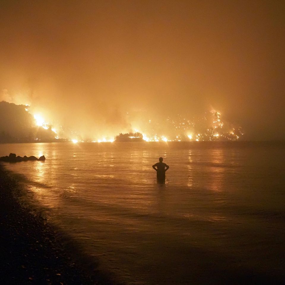 Ein Mann beobachtet Waldbrände am Strand von Kochyli in Griechenland