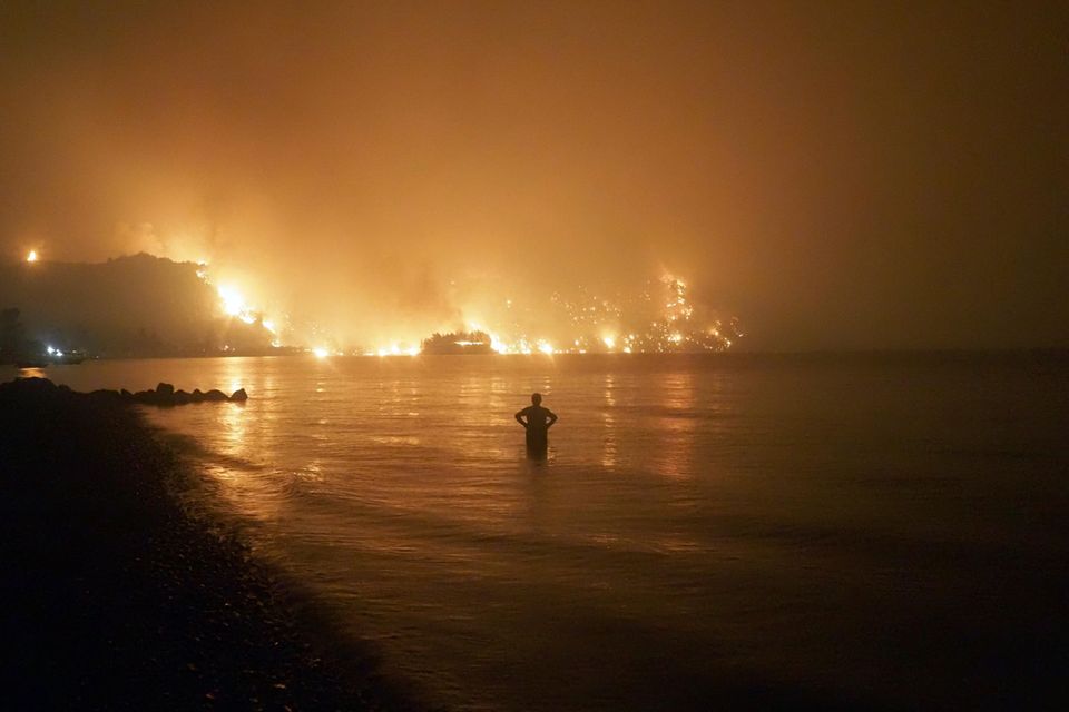 Ein Mann beobachtet Waldbrände am Strand von Kochyli in Griechenland