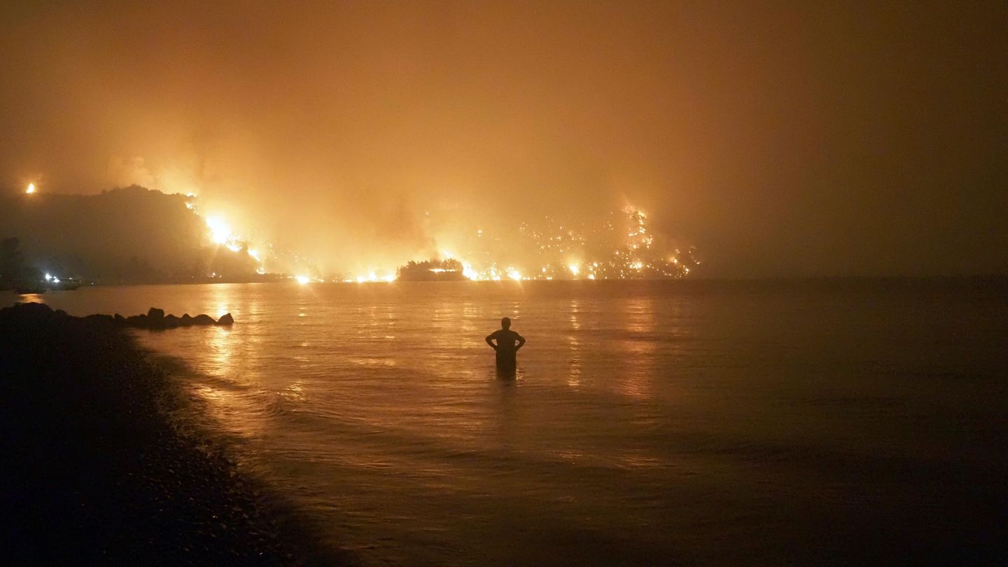 Ein Mann beobachtet Waldbrände am Strand von Kochyli in Griechenland