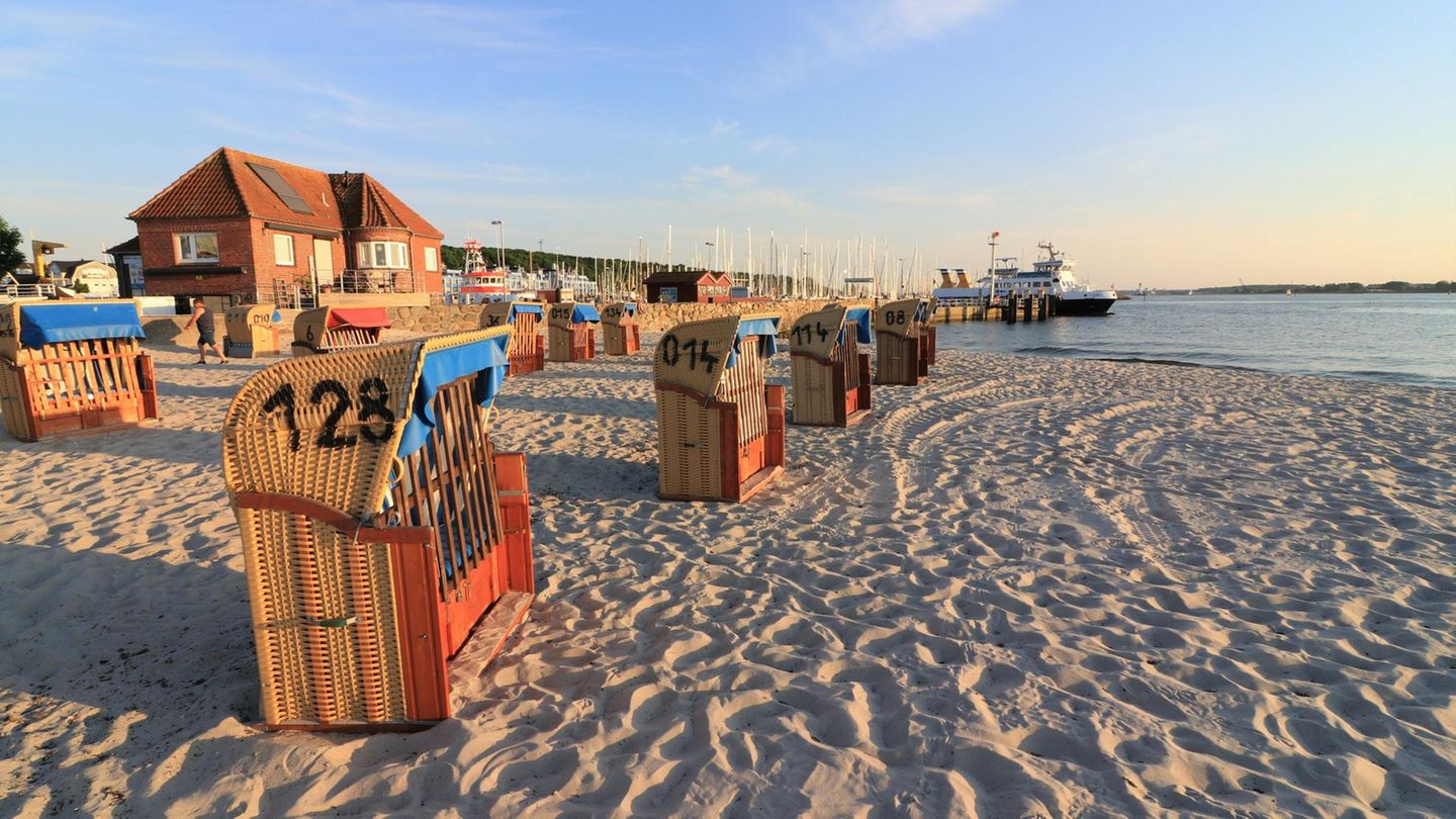 Strand von Laboe bei Sonnenuntergang mit Strandkörben und Yachthafen im Hintergrund