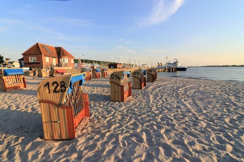 Strand von Laboe bei Sonnenuntergang mit Strandkörben und Yachthafen im Hintergrund