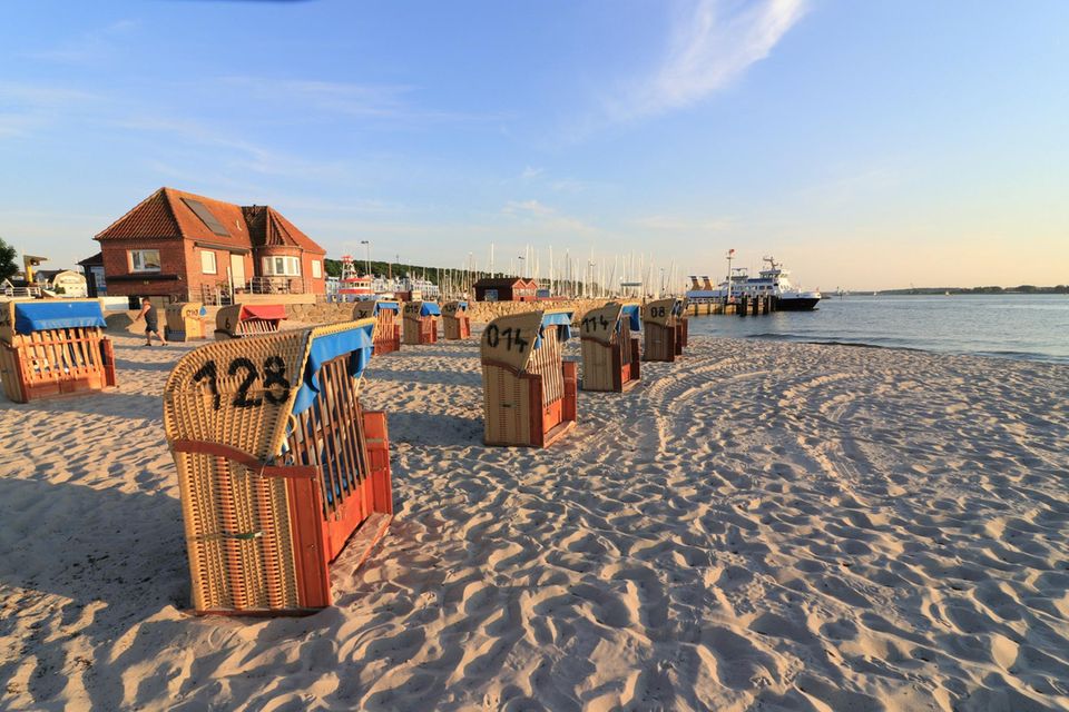 Strand von Laboe bei Sonnenuntergang mit Strandkörben und Yachthafen im Hintergrund