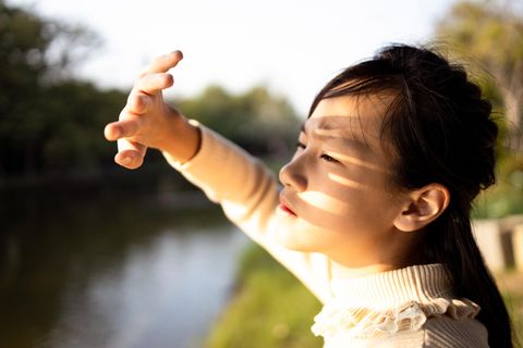 Frau hält sich die Hand vor das Gesicht, um sich vor der Sonne zu schützen