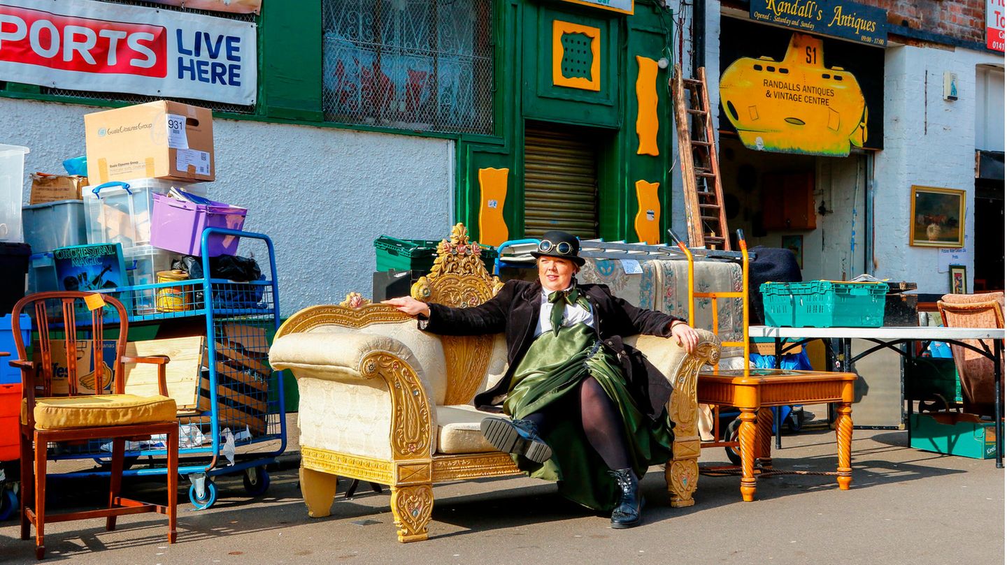 Eine bunt gekleidete Frau sitzt auf einem alten Sofa im Barras Market