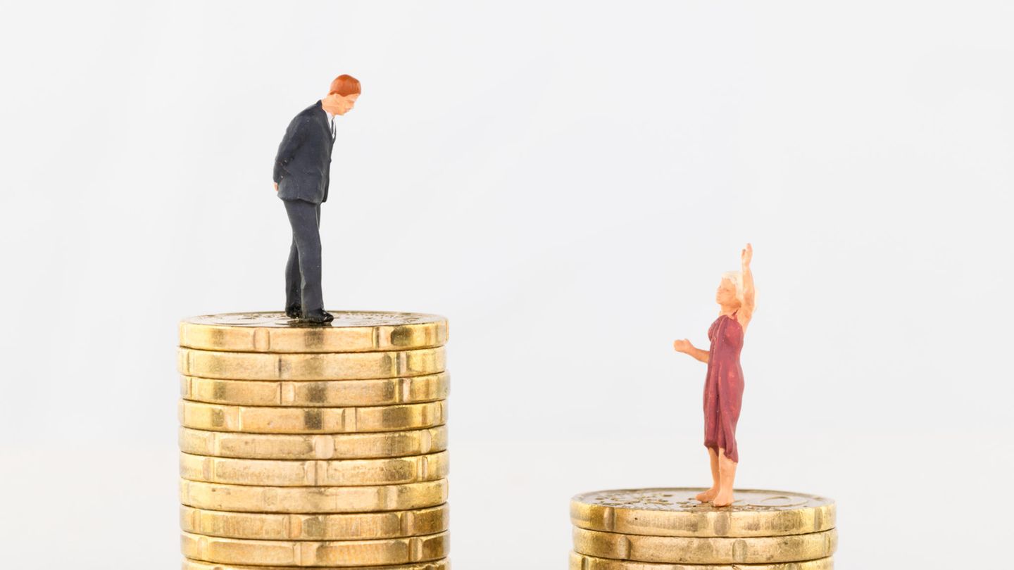 Zwei Miniaturfiguren stehen auf unterschiedlich hohen Münzstapeln