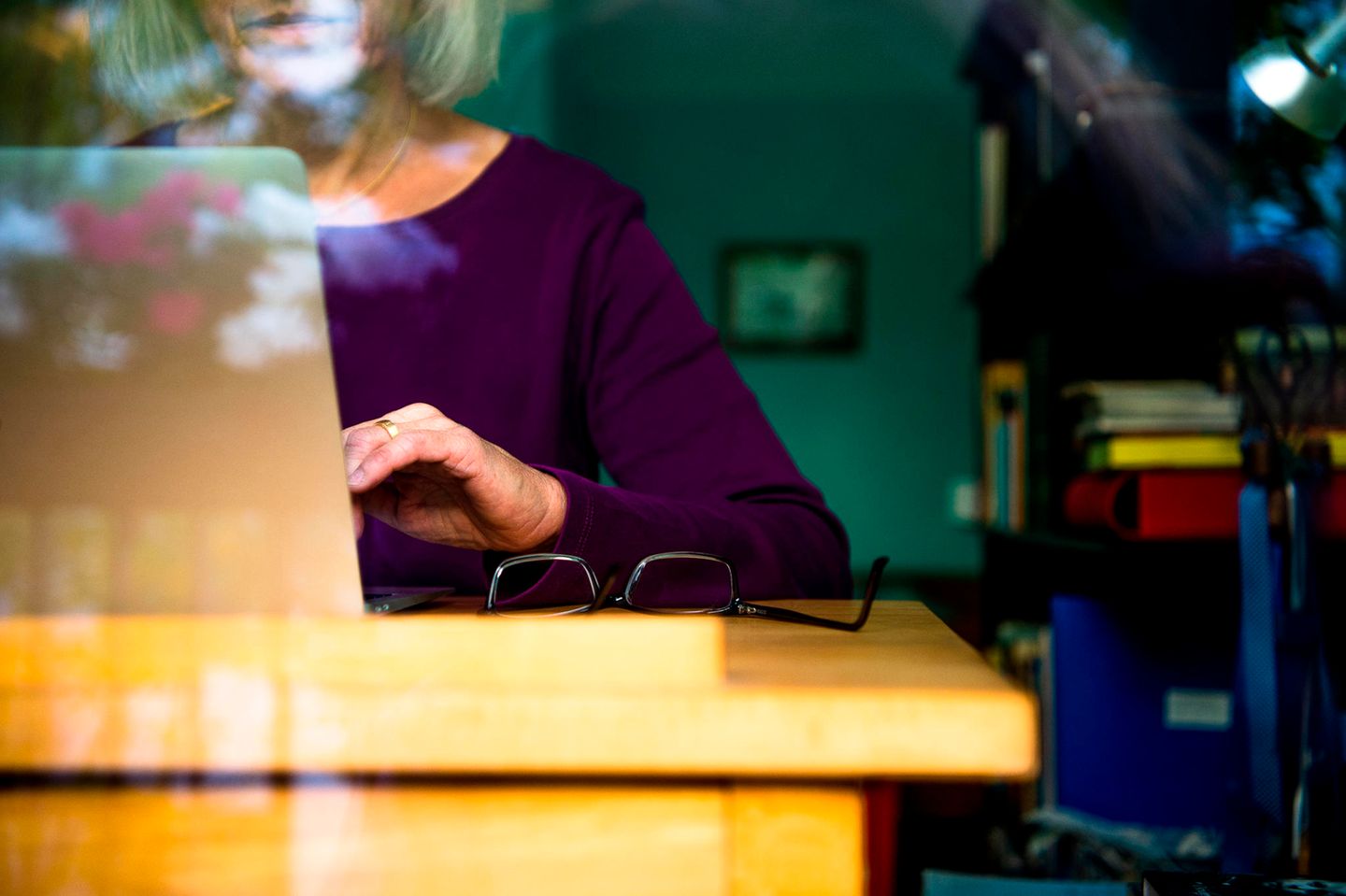 Eine Frau sitzt zuhause an einem Schreibtisch und arbeitet an einem Laptop.