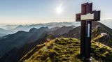 Gipfelkreuz Schöngütsch und Berge bei Sonnenaufgang vom Brienzer Rothorn aus gesehen