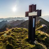 Gipfelkreuz Schöngütsch und Berge bei Sonnenaufgang vom Brienzer Rothorn aus gesehen