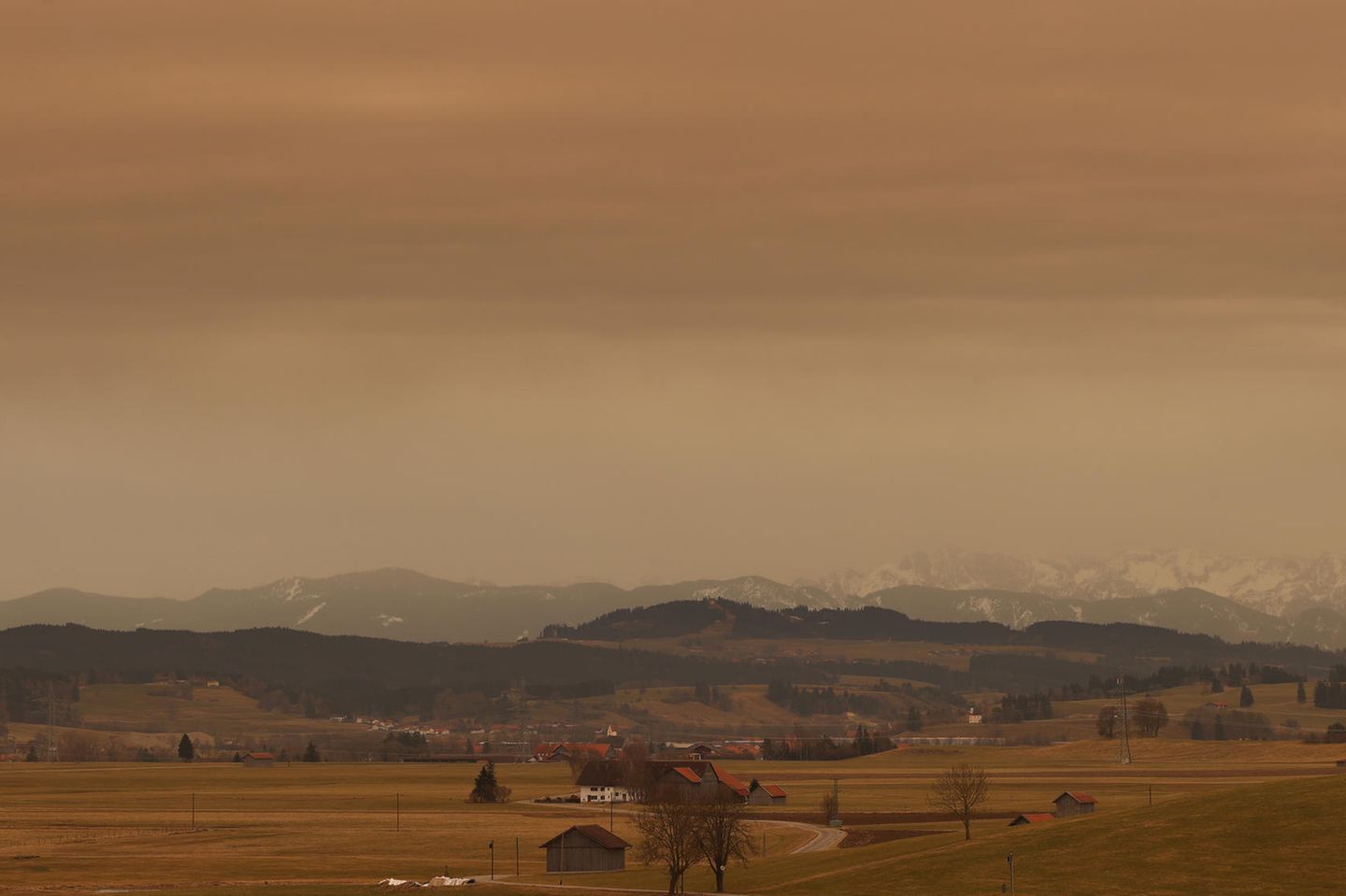 Bayern, Ruderatshofen: Saharastaub färbt den Himmel in rötliche Farbtöne