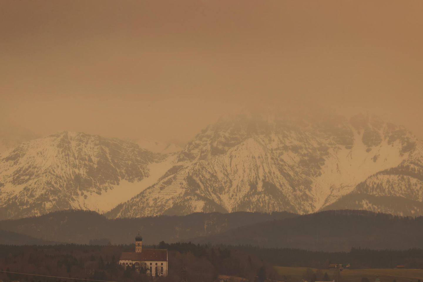 Saharastaub färbt den Himmel über der Stadtpfarrkirche Sankt Martin in Marktoberdorf gelb