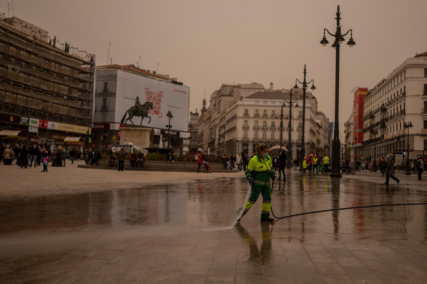 Madrid: Mitarbeiterin der Stadtreinigung reinigt den Sol-Platz von Wüstensand aus der Sahara mit Wasserschlauch