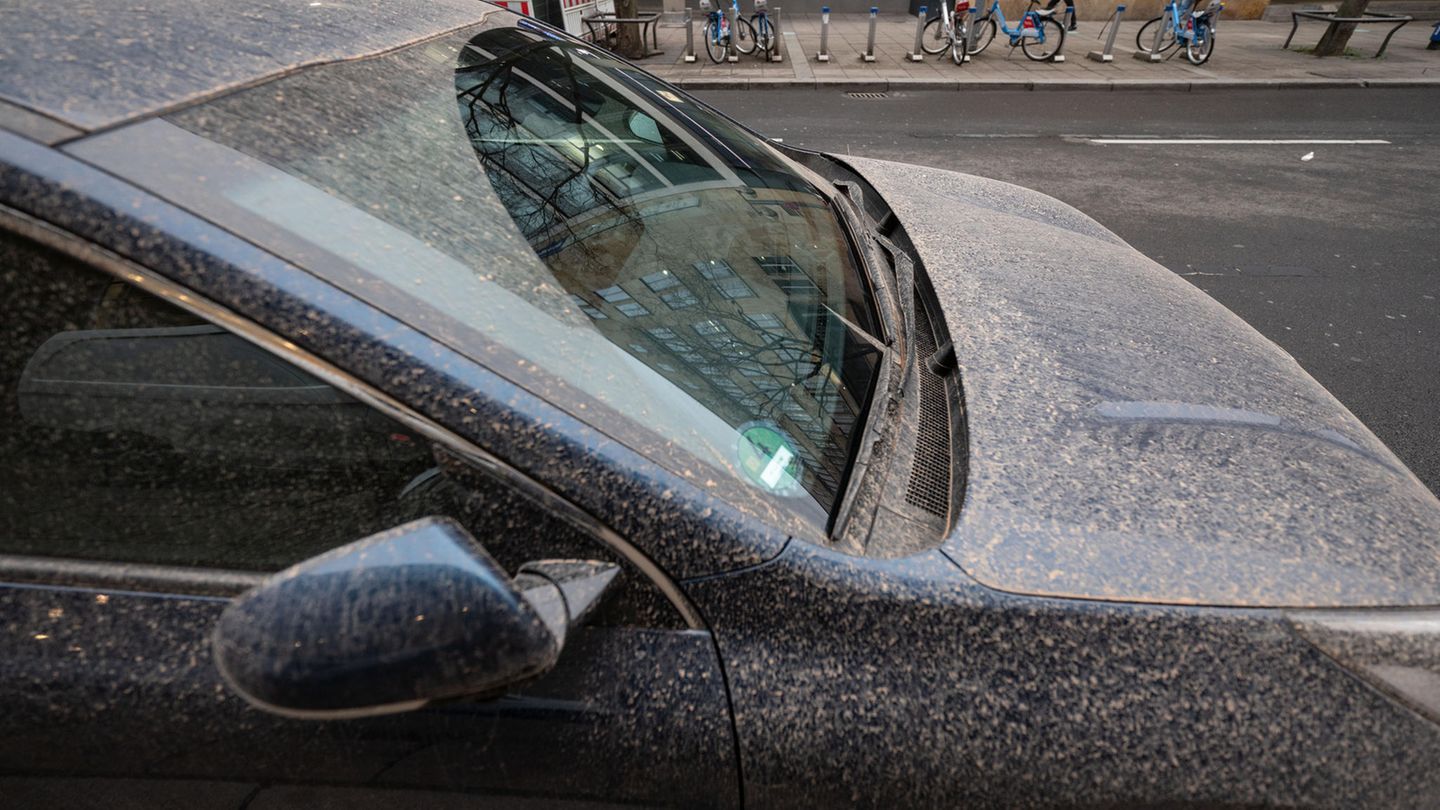 Ein Auto ist von rötlichem Staub bedeckt