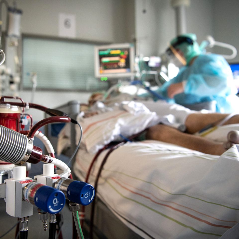 Eine Krankenschwester versorgt einen schwer an Corona erkrankten Patienten auf der Intensivstation des Klinikums in Fulda. Im Vordergrund steht eine ECMO-Maschine, an die der Mann angeschlossen ist. Viele Patienten mit schweren Verläufen liegen mehrere Wochen auf der Intensivstation, rund die Hälfte der künstlich beatmeten Patienten stirbt