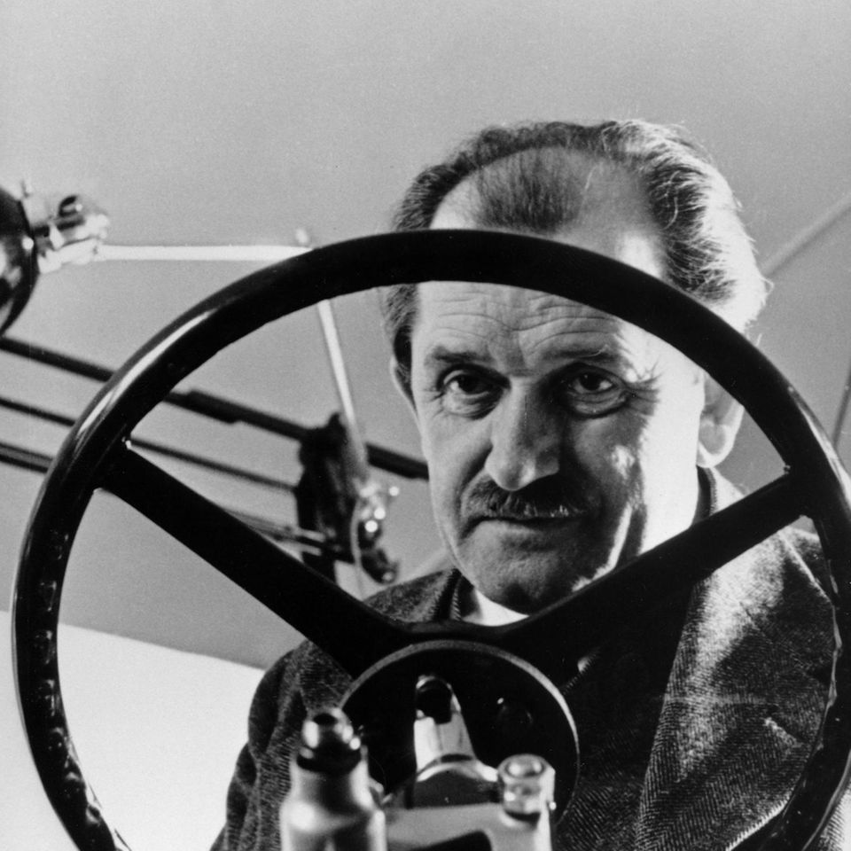 Ferdinand Porsche hinter einem Lenkrad in der Werkstatt