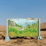 Image Name: Chahar Mahal and Bakhtiari Province – Kurd City – 2021  Photographer Name: Majid Hojjati  Year: 2022  Image Description: A painting of lush nature, with the clean climate of Chahar Mahal and Bakhtiari province’s past,  is located in the dry desert of this province. The sign reads: ‘I must remember not to do anything that is against the law of the Earth’.  Series Name: The Earth Belongings  Series Description: Life has meaning in human beliefs with its symbols. Mountains, forests, plains, free and beautiful creatures, and clear blue skies are all creations that will come to mind when we hear the word ‘life’. Where it is free from the fence of man, and there is no trace of human presence in it, it is ‘nature’. Where humans stepped in without understanding and respecting the spirit of nature, they endangered the existence of other beings. And then from this soil, nothing but a lifeless body will remain. The mountains will forget the flight of the eagles, and the noble howls of the horses will not be heard in the plains; and even the lion, that king of the forest, will be only a name in the books. These elements belong to the planet and are inseparable from it, without them what is left is a cold, lost and distorted image that no longer resembles anything. Maybe it's time to weigh what we have taken from nature and what we have given it and measure what we have done with the universe.