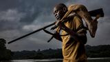Image Name: Hunters 1  Photographer Name: Brent Stirton  Year: 2022  Image Description: <p>DOUME VILLAGE, LASTOURSVILLE, GABON, 29 JUNE 2021: Expert bushmeat hunter Nkani Mbou Mboudin is seen with an antelope he just shot hunting in the forest around his village. This village survives on fishing and bushmeat. Gabon has a sustainable bushmeat culture, largely because of its small population and large protected habitats.</p>  Series Name: Bushmeat Hunters  Series Description: This is a series of bushmeat hunter portraits taken in Guyana, Gabon, the Democratic Republic of Congo and the Republic of Congo. These men are seen in an age-old act, bringing animals they have hunted back to their villages. Some of these men are hunting for other, wealthier men who have employed them, others are hunting for their families. In all cases, very little of what they hunted was consumed in the village. Bushmeat commands a high price, which increases as it gets to major cities. These days, hunting of this kind is almost always about an economy of supply and demand.