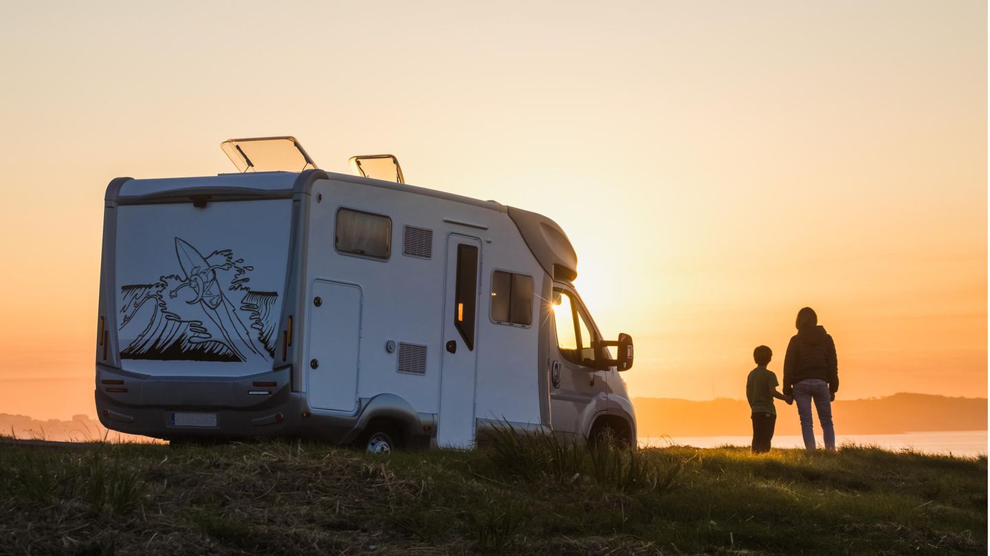 Mutter und Sohn stehen vor einem Wohnmobil und gucken auf den Sonnenuntergang