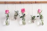 Blumen in alten Gläsern, die von einer Stange hängen