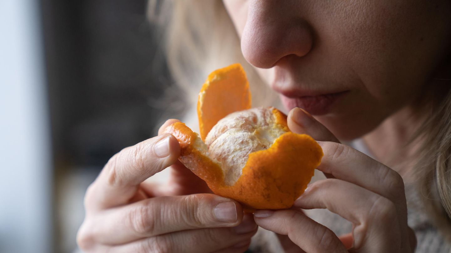Eine Frau riecht an einer Mandarine