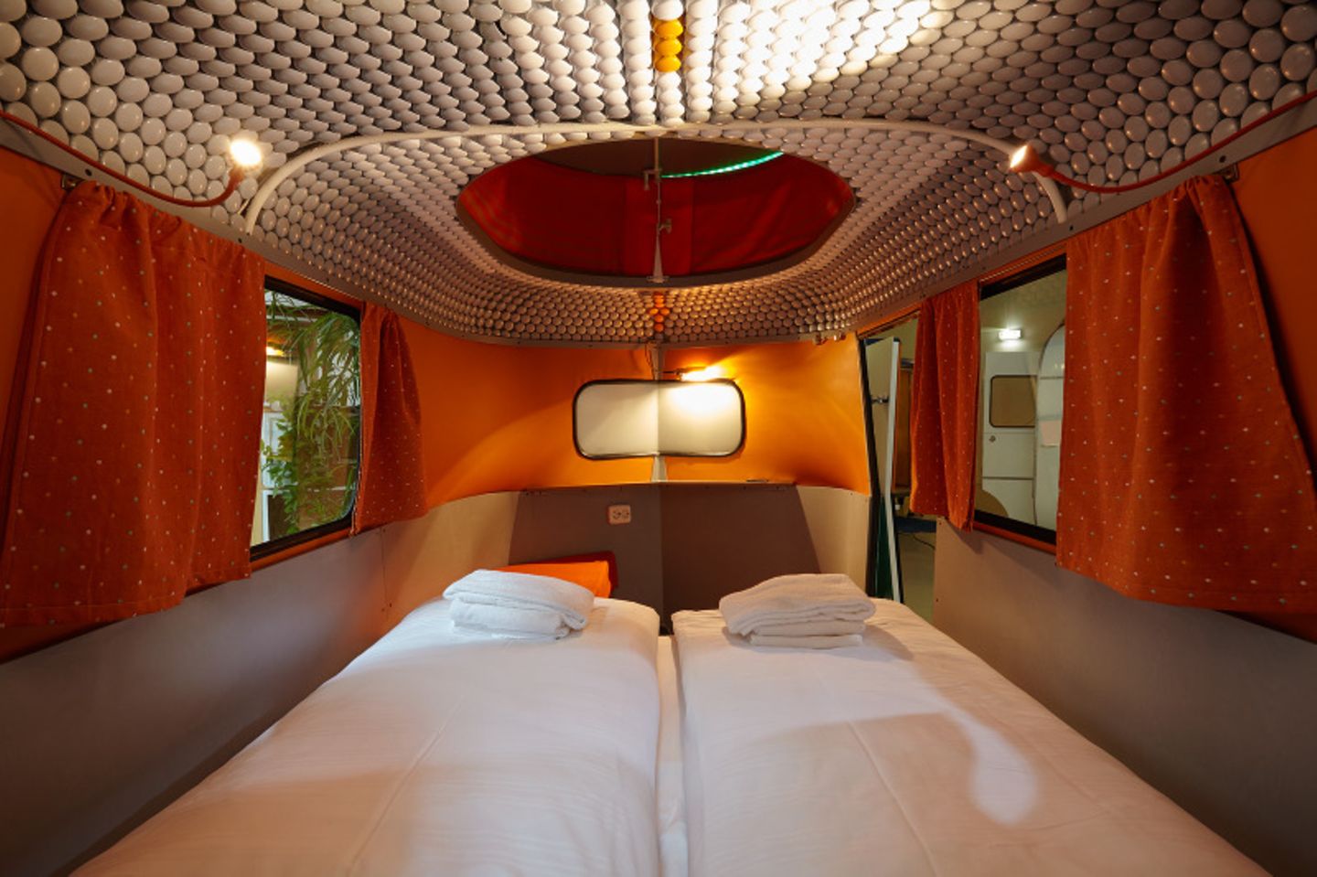 Innenansicht eines Campers mit roten Vorhängen und warmem Licht