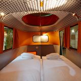 Innenansicht eines Campers mit roten Vorhängen und warmem Licht