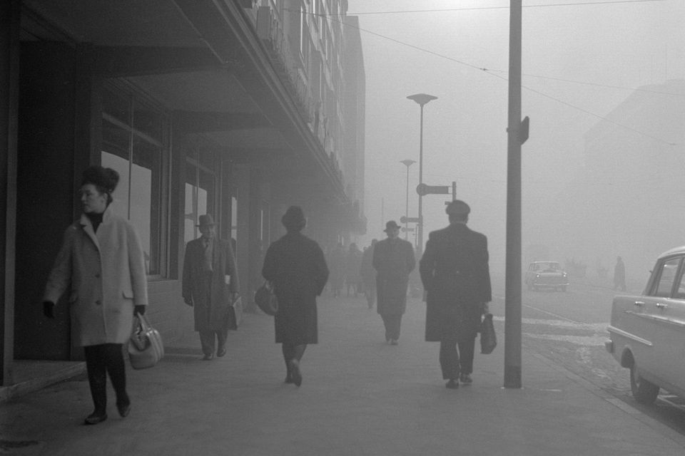 Personen laufen auf einer Straße in Gelsenkirchen durch Smog