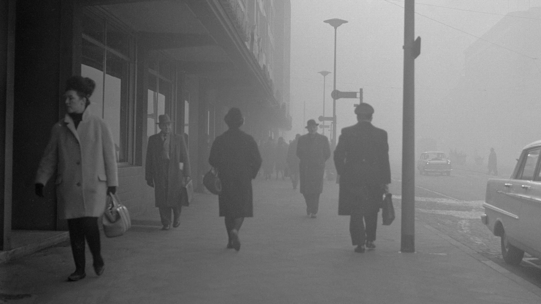 Personen laufen auf einer Straße in Gelsenkirchen durch Smog