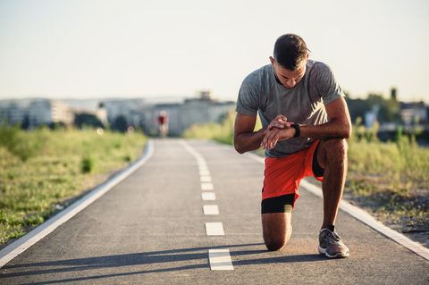 Pulsuhr im Einsatz: Ein Mann in sportlicher Kleidung macht sich bereit für seinen Lauf und liest etwas von seiner Pulsuhr ab.