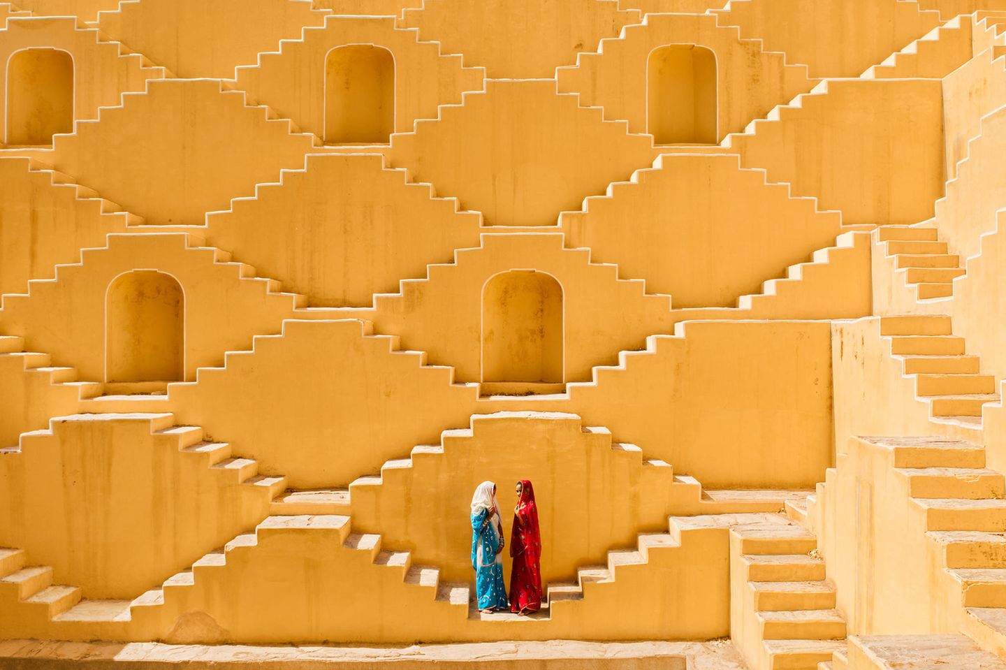 Auf diesem Foto pausieren Manisha und Jasmin Singh in einem Baori, einem alten Stufenbrunnen. Er befindet sich in einem Dorf in der Nähe der Stadt Jaipur außerhalb der indischen Thar-Wüste.      Ami Vitale, Fotografin und Filmemacherin des National Geographic Magazine, hat mehr als 100 Länder bereist und dabei nicht nur Gewalt und Konflikte, sondern auch surreale Schönheit und die fSchöpfungskraft der Menschen festgehalten