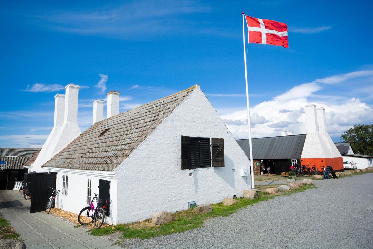 Weiß getünchte Räucherei mit dänischer Flagge im Vordergrund