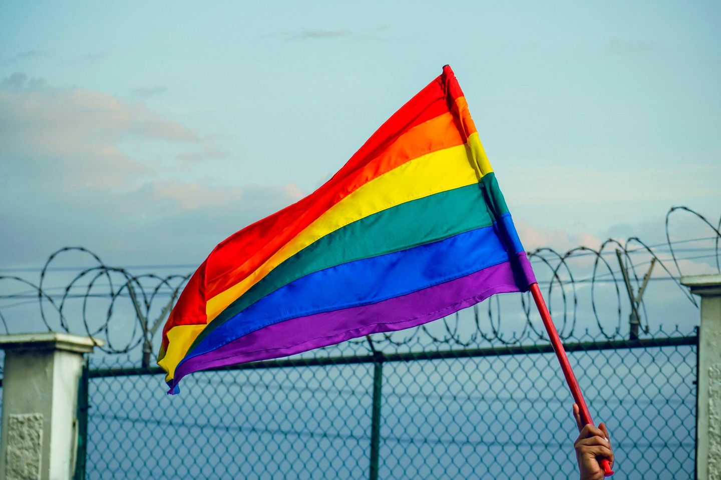 Regenbogen-Fahne weht vor Zaun