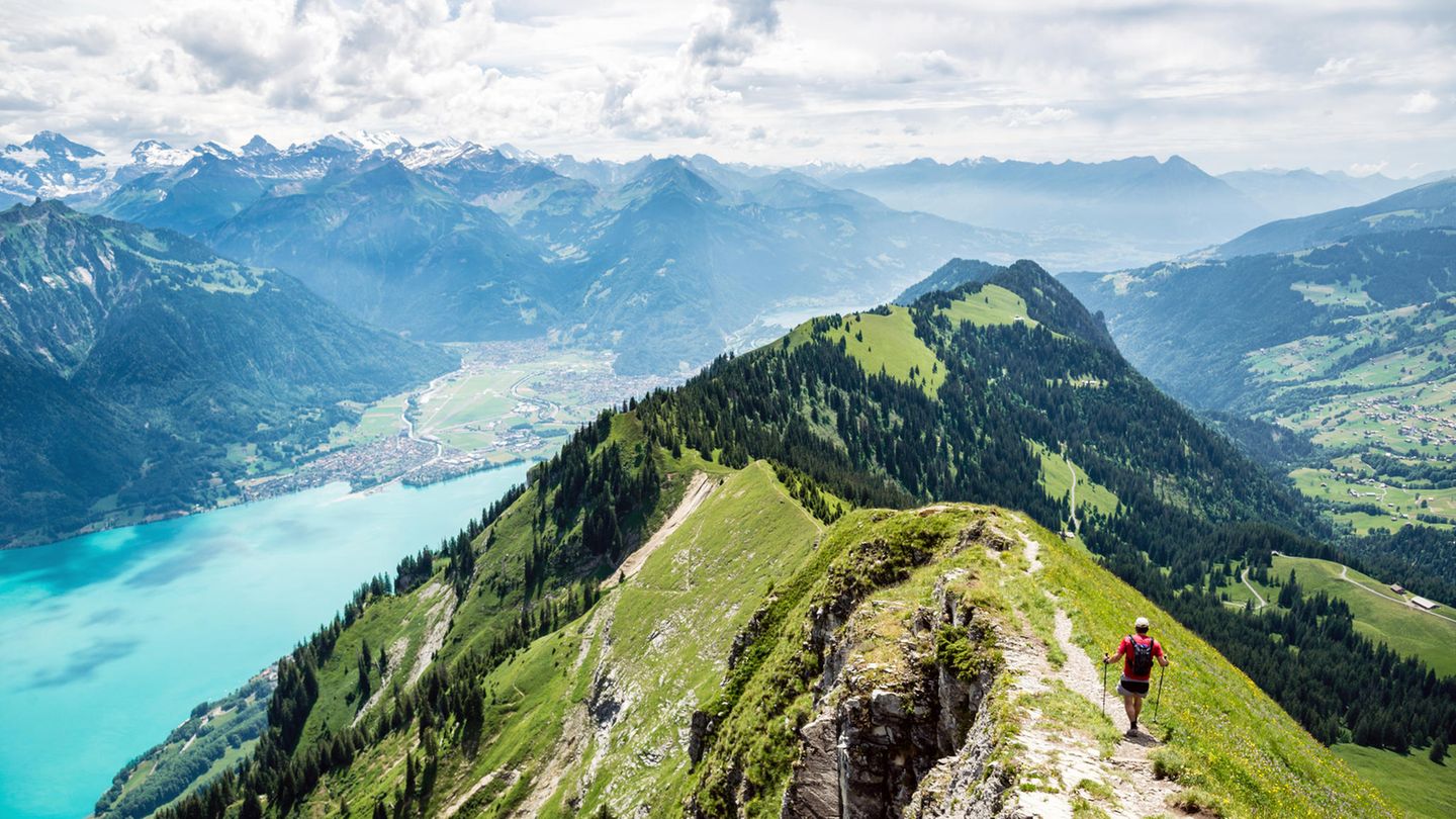 Mann wandert auf einem Berggrat, unterhalb schimmert ein See türkis