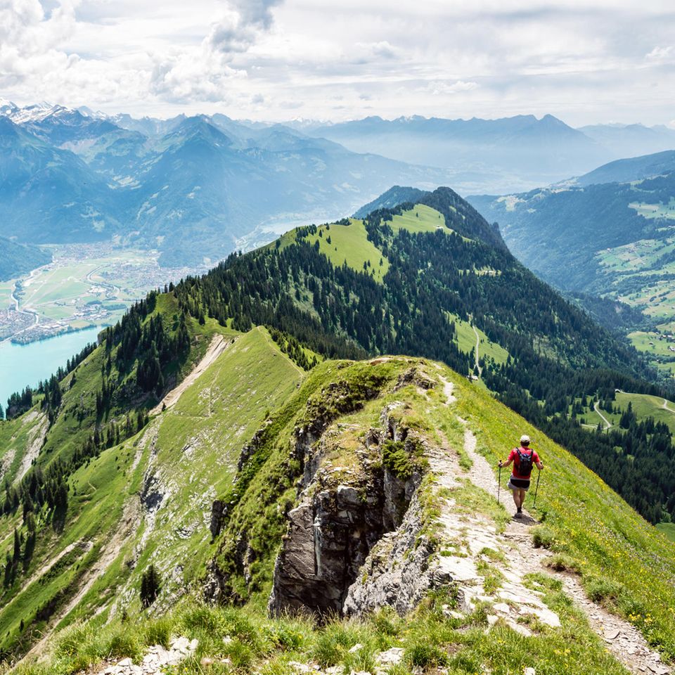Mann wandert auf einem Berggrat, unterhalb schimmert ein See türkis