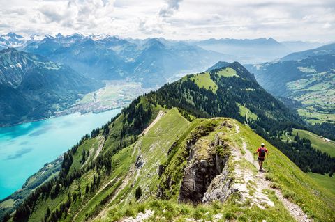 Mann wandert auf einem Berggrat, unterhalb schimmert ein See türkis