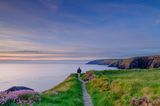 Mann auf dem Pembrokeshire Coast Path bei Sonnenuntergang