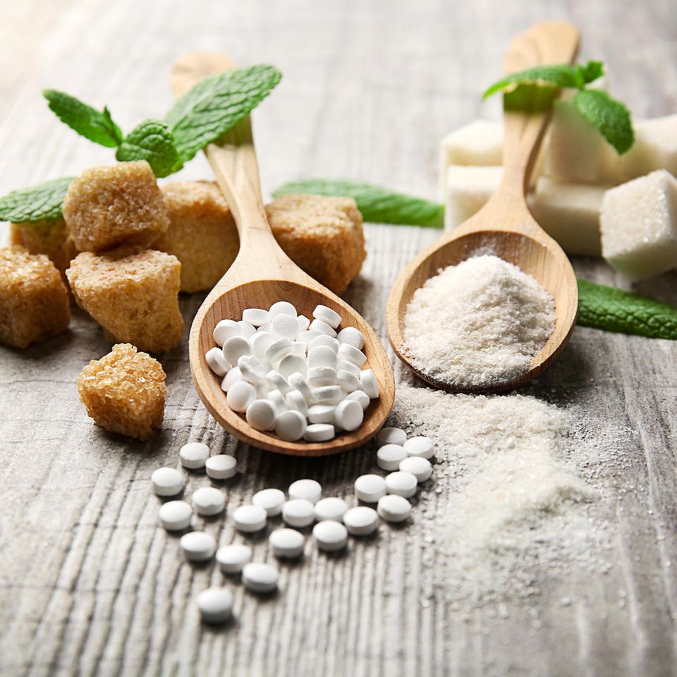 Braune Zuckerwürfel neben Stevia und anderen Zuckerersatzprodukten.