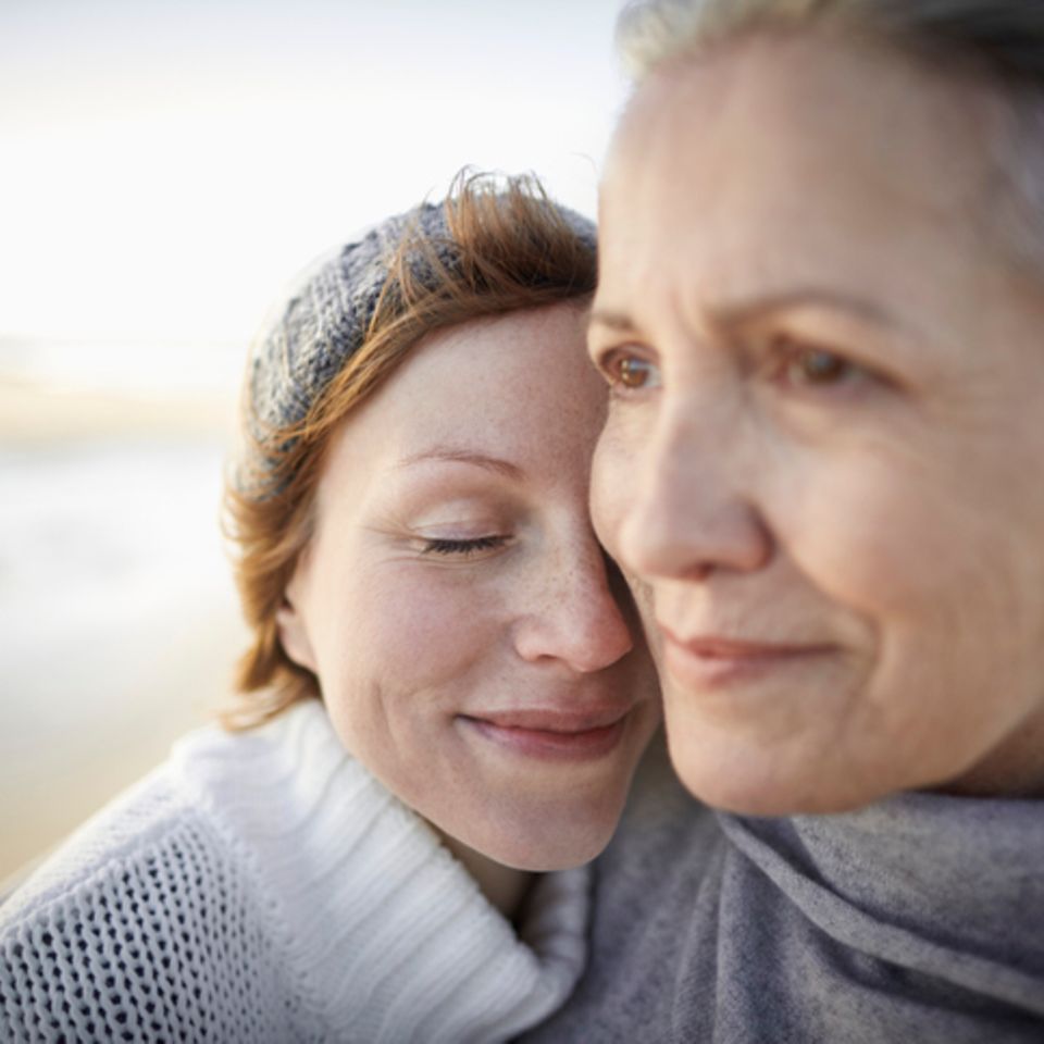 Mutter und Tochter umarmen sich am Strand