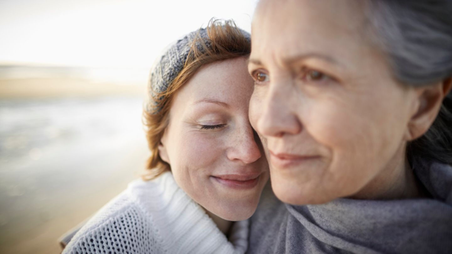 Mutter und Tochter umarmen sich am Strand